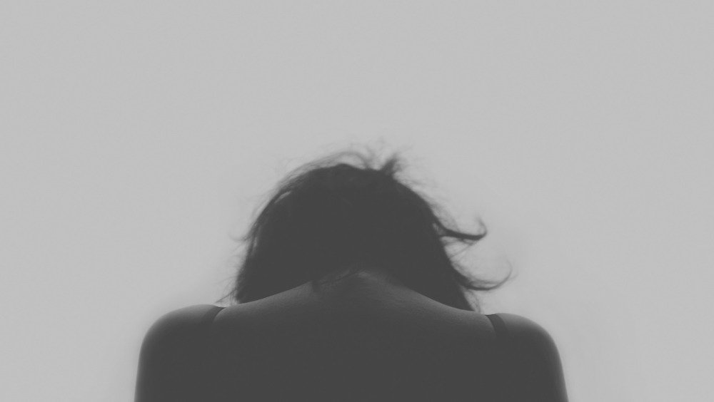 Sad woman with head down in black and white