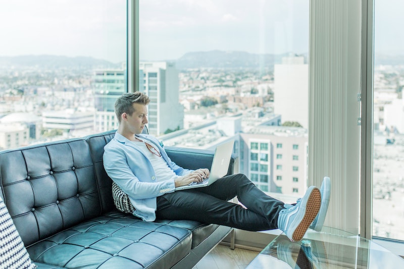 Man sitting on modern couch with laptop